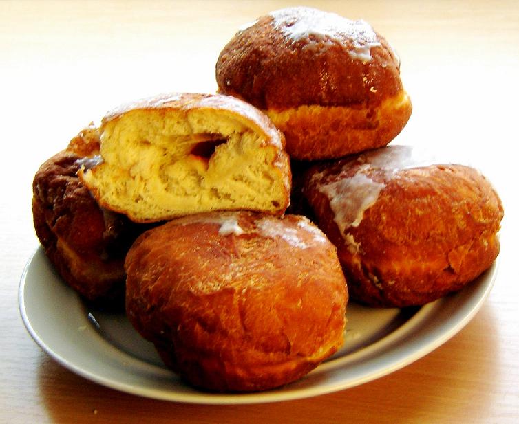 A pile of filled donuts, one torn open to show the jam inside