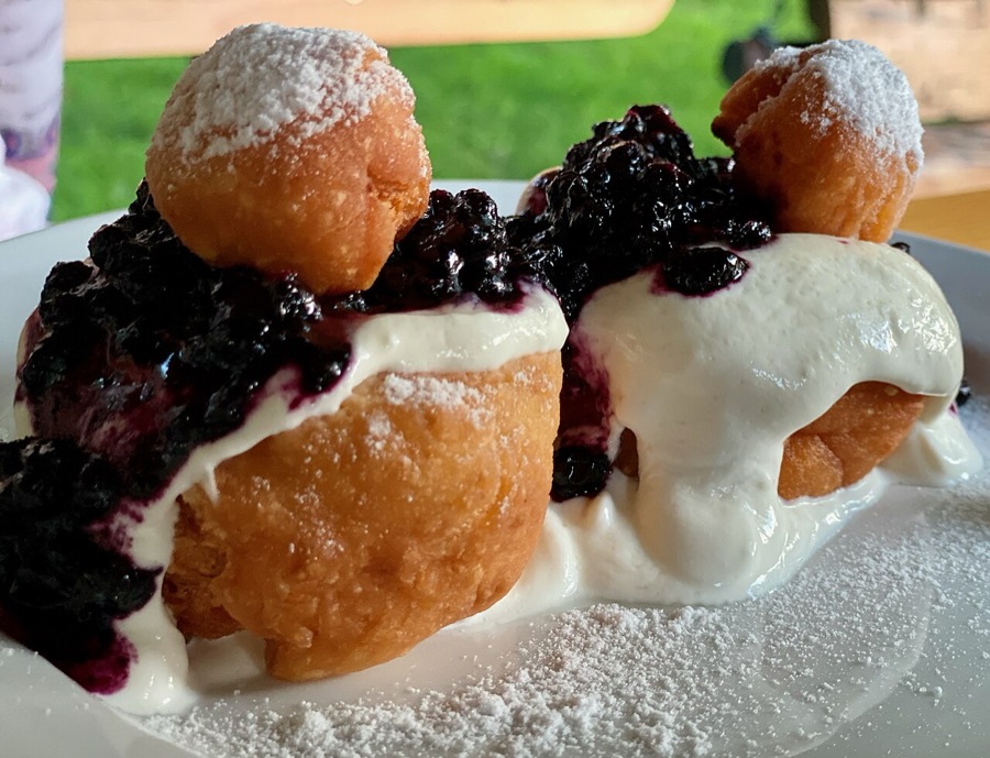 Papanași topped with sour cream, blueberry jam and a small dough ball